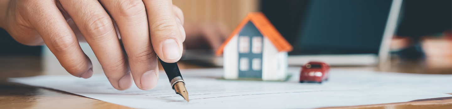 image of person's hand with pen...signing document with small house on top