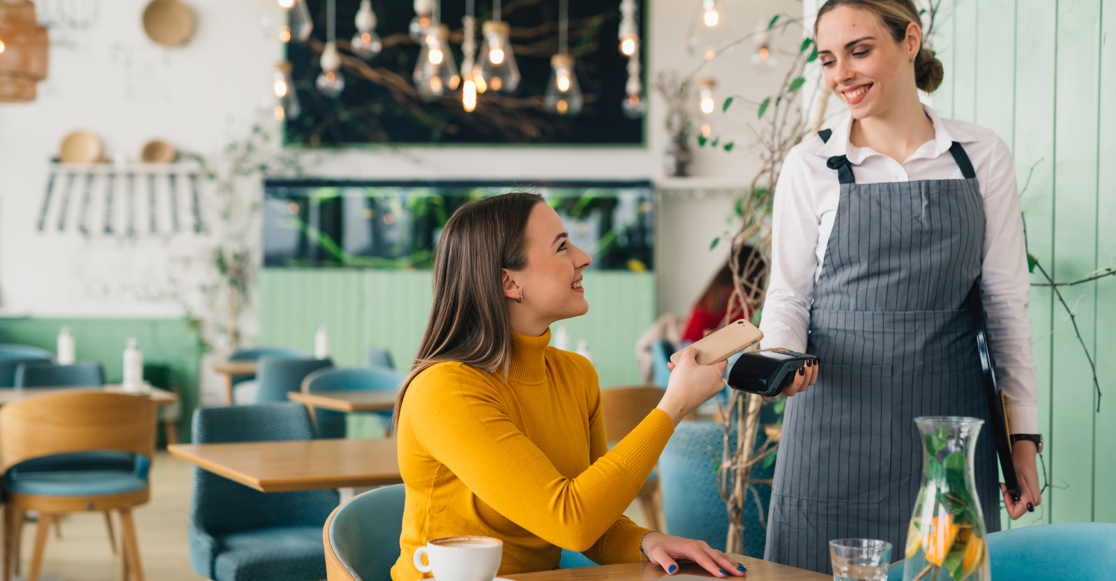 2 women in restaurant using mobile wallet 