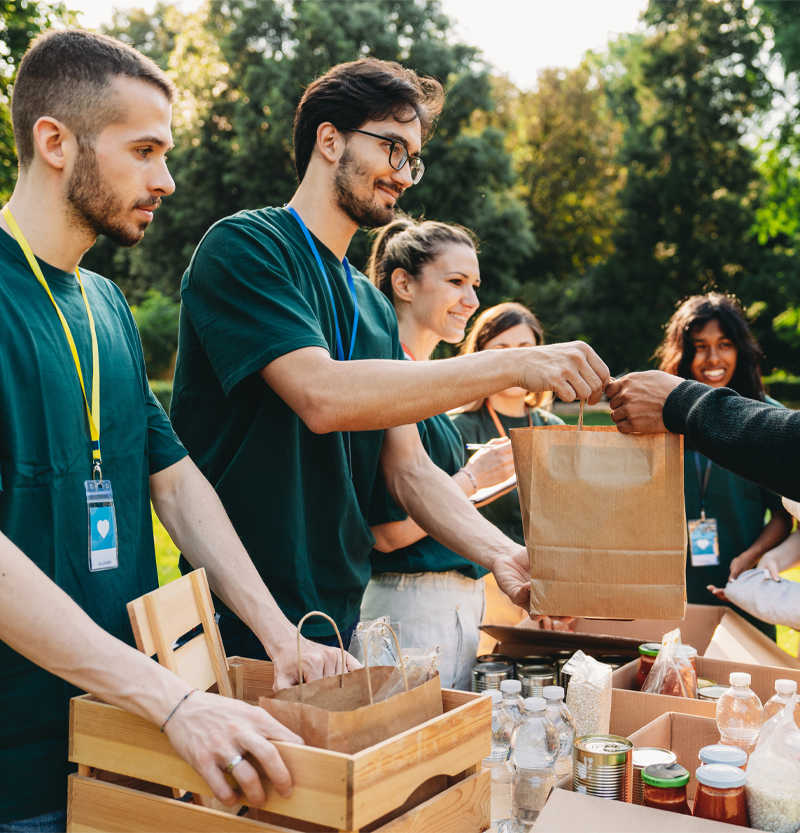 Volunteers providing full bag of supplies to person.