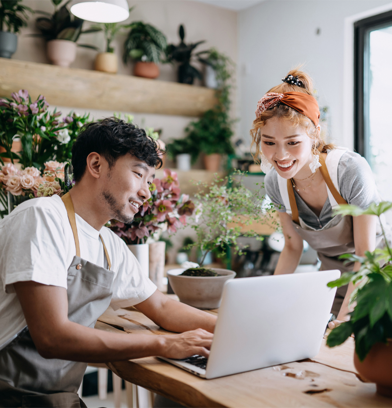 Man and woman smiling while looking at laptop.