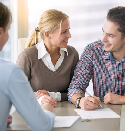 Couple working with lender on financing a home purchase and signing papers