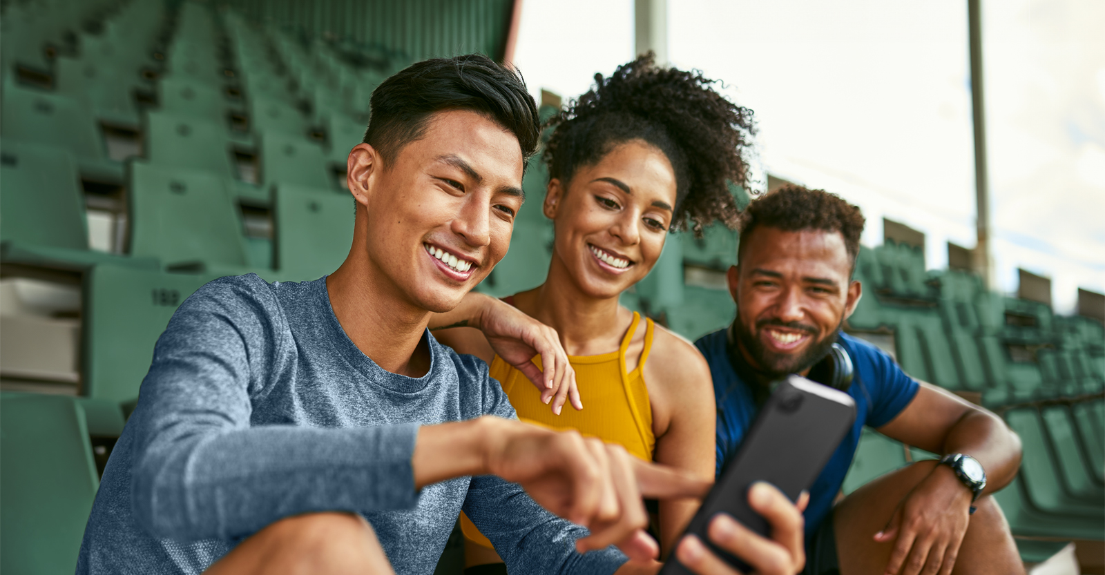 Group of friends smiling and pointing at smartphone.