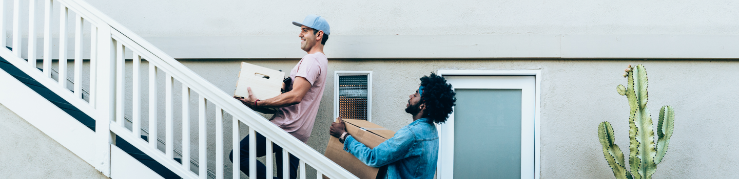 two guys carrying boxes up stairway