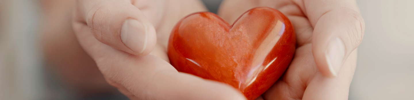 a red plastic heart in someone's hands