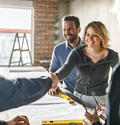 Couple shaking hands with builder who is working on their home