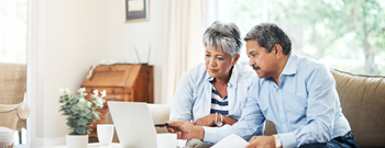 Couple on sofa with computer looking at finances